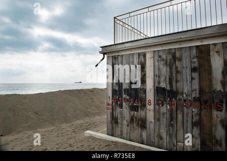 Facades covered with wooden planks to protect against winter weather and storms of the sea, in front of the building a sand dune, on the bottom an oil Stock Photo