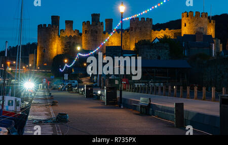 Conwy Castle and Quay on the River Conwy, North Wales. The bright lights come from the Nicola Faith Fishing Boat. Image taken in  Autumn 2018. Stock Photo