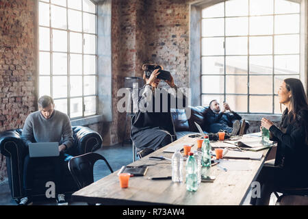 Designers testing virtual reality headset in communal space in studio Stock Photo