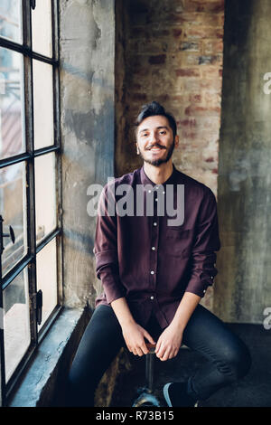 Man sitting on swivel stool by window Stock Photo