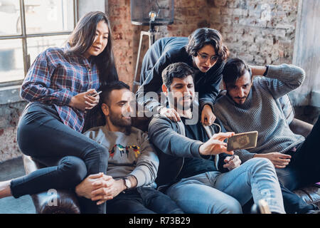 Group of colleagues on sofa taking selfie Stock Photo