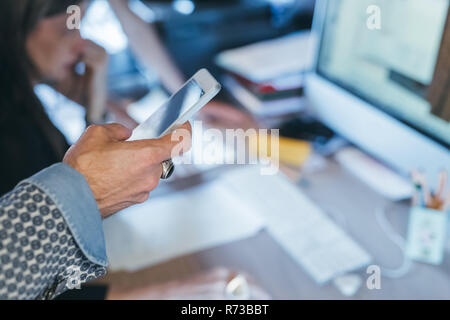 Man using cellphone at desk Stock Photo