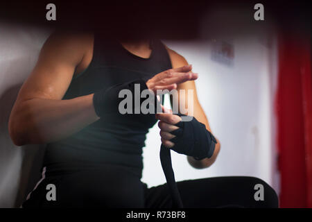 Female boxer putting on handwrap Stock Photo