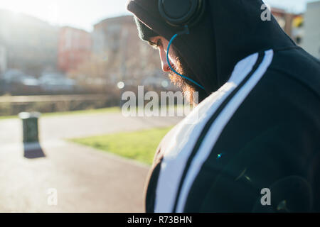 Man in hoodie using headphones Stock Photo