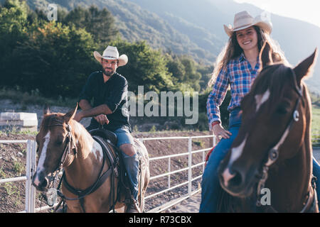 Cowgirl and boy on horseback in equestrian arena, portrait, Primaluna, Trentino-Alto Adige, Italy Stock Photo