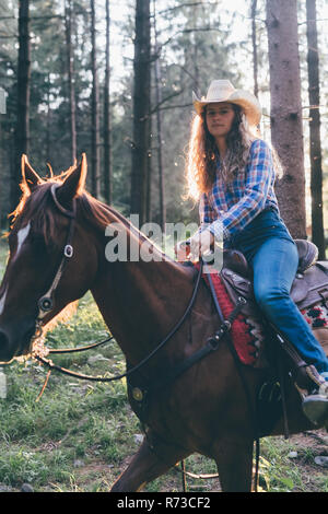 Cowgirl on horseback in forest, backlit portrait, Primaluna, Trentino-Alto Adige, Italy Stock Photo