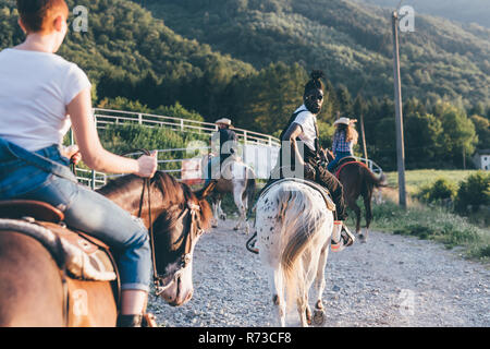 Adult friends riding horses on rural dirt track, rear view, Primaluna, Trentino-Alto Adige, Italy Stock Photo