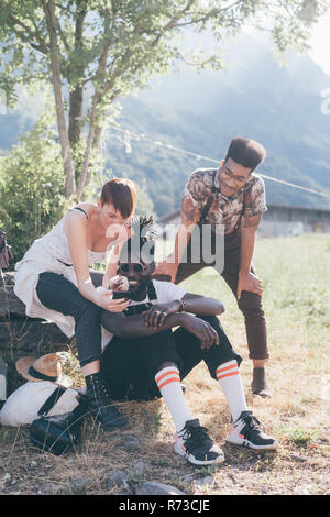 Three young adult hikers in field looking at smartphone, Primaluna, Trentino-Alto Adige, Italy Stock Photo