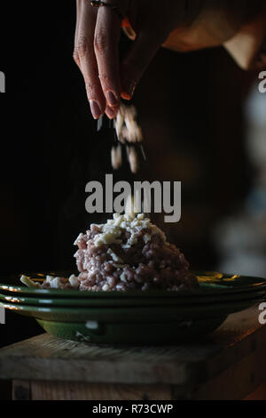 Young woman adding garnish to bowl of risotto, close up of hand Stock Photo