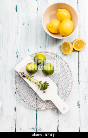 Bowl of lemons with limes on chopping board, still life, overhead view Stock Photo