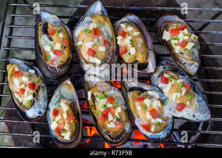 Mussels on the grill.Delicious festive barbecue on sand beach in the evening.Food and holiday concept. Stock Photo