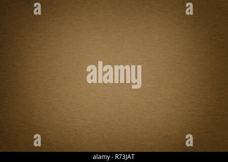 Texture of vintage dark brown paper background with vignette. Structure of dense bronze kraft cardboard with frame. Felt gradient backdrop closeup. Stock Photo