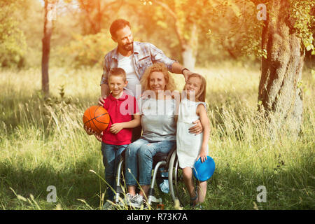 Family portrait. Woman in a wheelchair with her family outdoors. Stock Photo