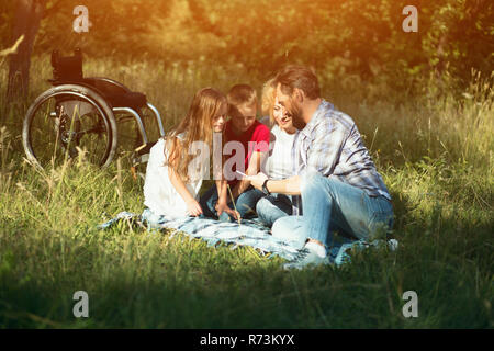 Happy family taking selfie on the picnic in park. Paraplegic Stock Photo