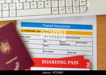 Travel insurance form with boarding pass tickets, passport keyboard on wooden table. Agencies sell airplane tickets or travel packages and allow consu Stock Photo