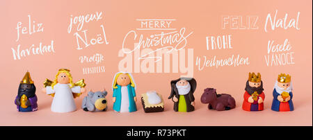 the holy family, an angel and the magi, and the text merry christmas in different languages, such as spanish, french, portuguese, czech or german, on  Stock Photo