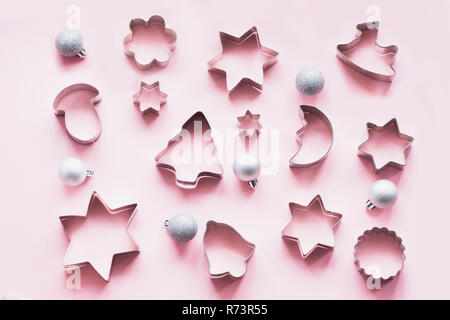 Various Christmas-themed cookie cutters on pastel pink. Holiday card. Top view and flat lay. Xmas pattern. Stock Photo