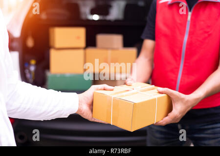 Asian male movers unloading boxes from van outdoors Stock Photo