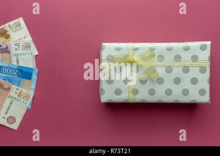 Russian ruble money with gift box with gold bow isolated on purple background Stock Photo