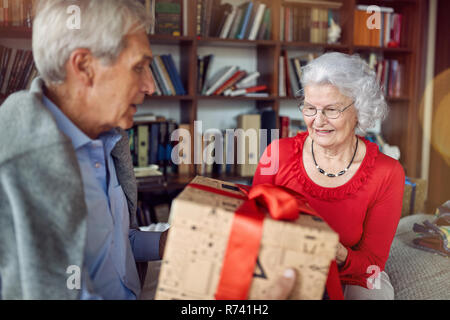 Happy lovely senior couple exchanging presents on Christmas Stock Photo