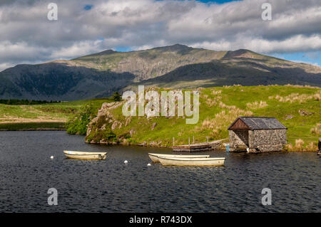 Boats moored on a small lake near Rhyd Ddu, with Snowdon mountain rising behind, in the Snowdonia National Park in north Wales. Stock Photo