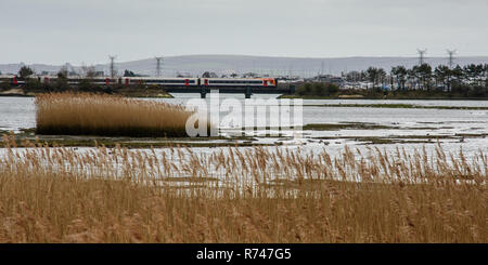 Poole, England, UK -March 17, 2017: A South Western Railway passenger train crosses Holes Bay nature reserve in Poole Harbour in Dorset. Stock Photo