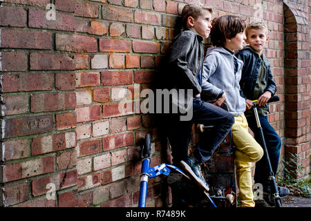 Boys leaning against brickwall Stock Photo