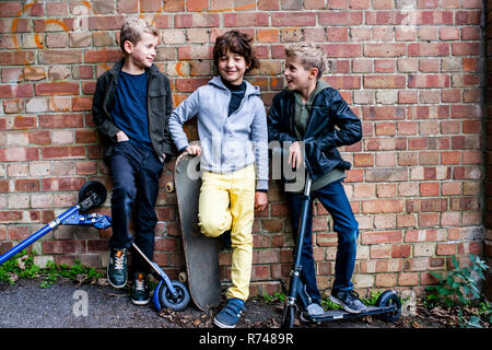 Boys leaning against brickwall Stock Photo