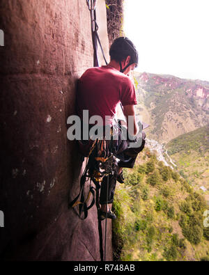 Rock climber sitting by rock face, Liming, Yunnan, China Stock Photo