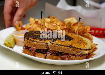 Completed Reuben sandwich with potato chips and sauce with a dill pickle. Stock Photo