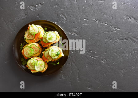 Tasty sandwiches with salmon, scrambled eggs and cucumber slices on black stone background with copy space. Top view, flat lay Stock Photo