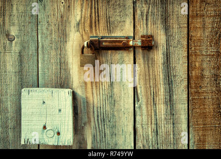 Old wooden door locked with rusty door latch and padlock. Stock Photo