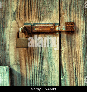 Old wooden door locked with rusty door latch and padlock. Stock Photo