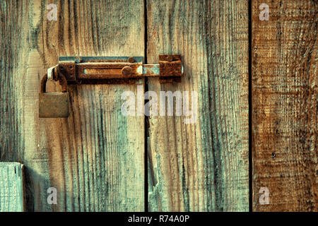Old wooden door locked with rusty door latch and padlock. Stock Photo