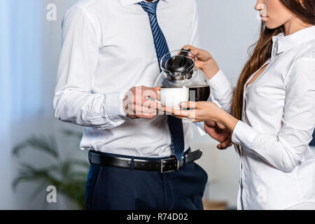 cropped image of girlfriend pouring coffee into boyfriend cup in morning at home, social role concept Stock Photo