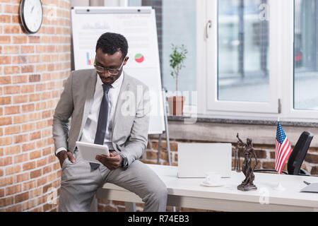 African american businessman looking at digital tablet with hand in pocket Stock Photo