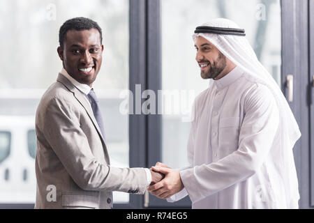 close up view of african american businessman and arabic partner shaking hands in office Stock Photo