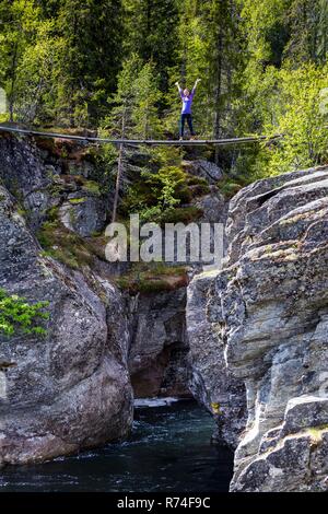 girl standing on suspension bridge. Canyon View at tre world famous waterfall Rjukandefossen, Norway Stock Photo