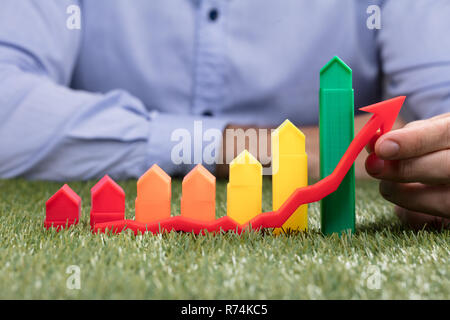 Person Holding Red Arrow In Front Of Increasing Graph Stock Photo