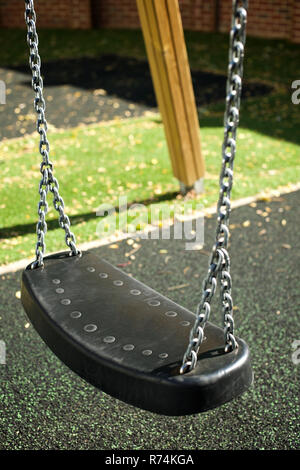 Children's swings in a playground with a rubber mat floor on a sunny day Stock Photo