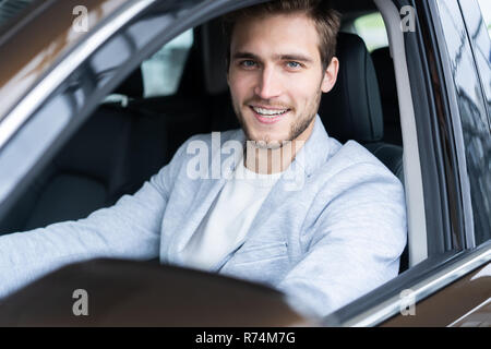 Visiting car dealership. Handsome man in his new car Stock Photo