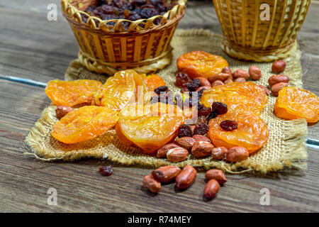 peeled raw peanuts dried apricots raisins on a wooden table background close-up Stock Photo