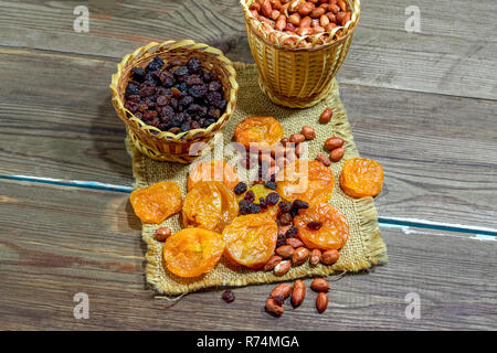 peeled raw peanuts dried apricots raisins on a wooden table background close-up Stock Photo