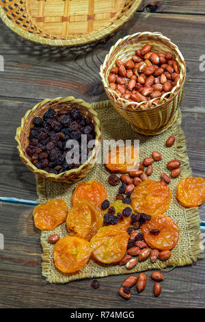 peeled raw peanuts dried apricots raisins on a wooden table background close-up Stock Photo