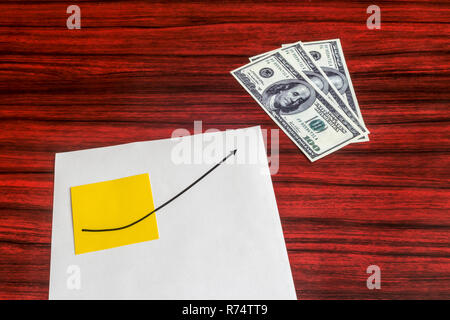 Curve graph printed on a sheet of paper and yellow note pointing a dollar bills. Stock Photo