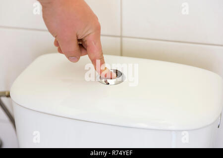 Finger pushing button and flushing toilet. Stock Photo