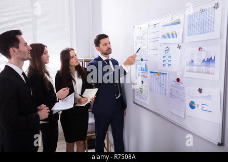 Businesspeople Analyzing Graphs On White Board Stock Photo