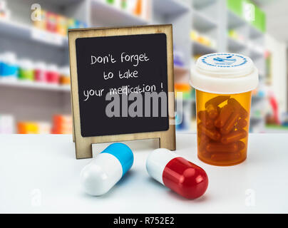 Informational Sign in a pharmacy, do not forget to take your medication,  on a whiteboard next to bottles of medicines, conceptual image Stock Photo