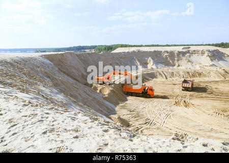 Work of the excavator and truck at a sand quarry. Excavator loading sand into a dump truck. Stock Photo