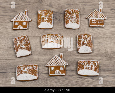 Group of ornate Christmas gingerbreads on wood background. Beautiful decorated gingerbread sweets in house shape and with hand-painted chapel in snow. Stock Photo